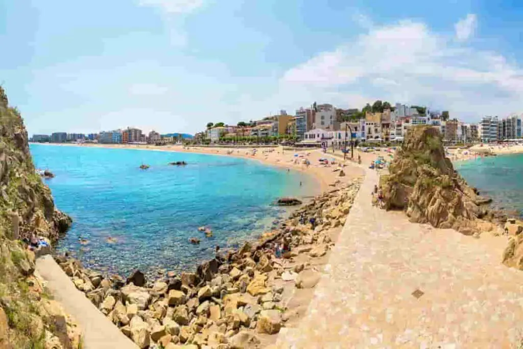 Barcelona beaches with boardwalk separating two beach areas and blue water on both sides, 2024 Best Towns Near Barcelona With A Beach: 15 Tops Spots, barcelona beach resorts, beach towns near barcelona, best coastal towns near barcelona, best beach towns near barcelona, beach resorts near barcelona, cities near barcelona, barcelona beach