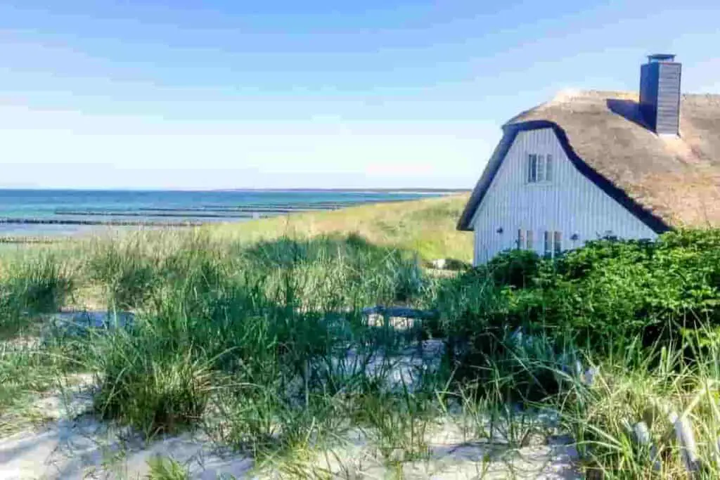 a thatched roof beach house next to the sand and sea, How Much Does it Cost to Rent a Beach House? Renting vs. Buying: [Surprising Facts] Guide to Vacation Rentals, how much are beach houses to rent, how much does a beach house cost, how much does a beach house cost to rent, how much is it to rent a beach house, how much to rent a beach house, how much is a beach house, how much does it cost to rent a beach house for a week