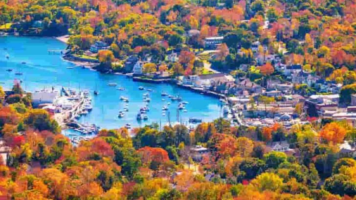 beautiful autumn colors surround a villiage and blue lake, 13 Prettiest Coastal Towns to Visit in Maine in Autumn-[Surprising Beautiful] Seaside