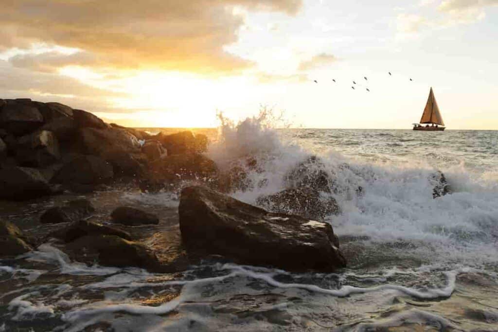 ocean seascape photography with seascapes showing sailboat and waves crashing on rocks