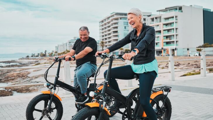 elderly man and woman on beach bikes smiling with buildings in the background, Best Beach Towns in the World to Retire - Surprising Towns
