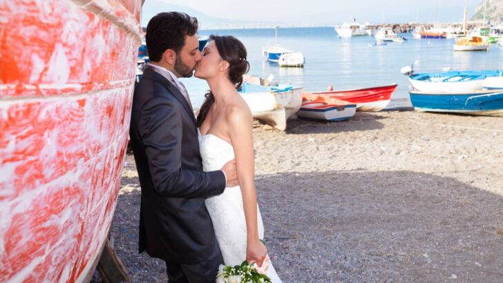 man and woman kissing next to a boat in a boat dock beach area in Italy, Italian Coastal Town Charms &ndash; Beach Towns Near Naples [Map Plus Best Beach], beach towns near naples, naples beach italy, naples italy beaches, towns near naples italy, beach towns near naples italy, best beach towns near naples italy, best towns near naples italy, best beach towns near naples