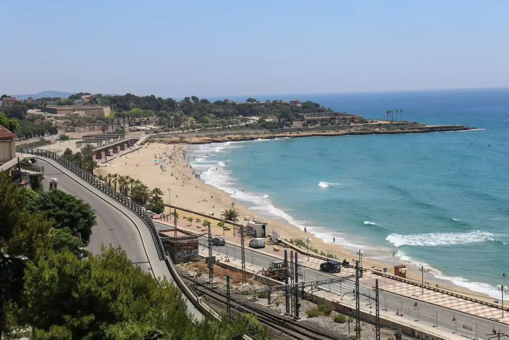 bird's eye photography of blacktop road near beach in spain, 2024 Best Towns Near Barcelona With A Beach: 15 Tops Spots, barcelona beach resorts, beach towns near barcelona, best coastal towns near barcelona, best beach towns near barcelona, beach resorts near barcelona, cities near barcelona, barcelona beach