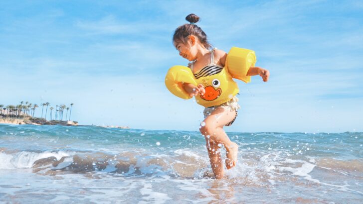 girl playing beside body of water during daytime