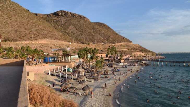 a beach with people and buildings, La Paz Beaches Mexico - 7 Amazing Beaches [Surprising Fun]